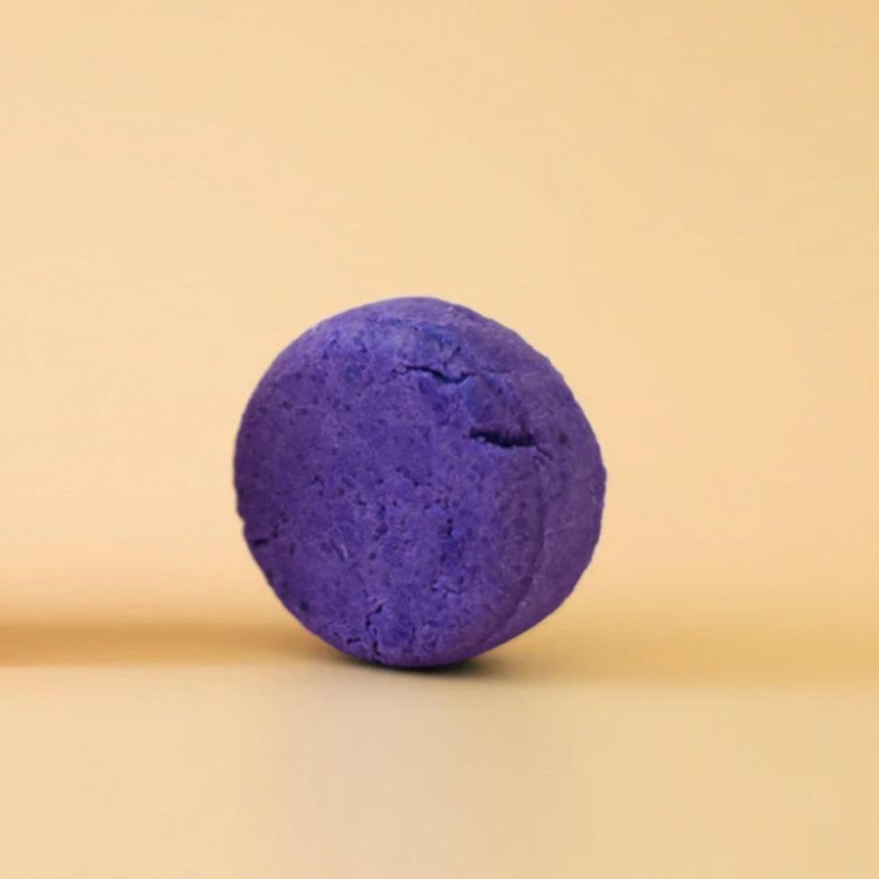 zero waste shampoo bar. The bar is a round deep purple toner shampoo bar.