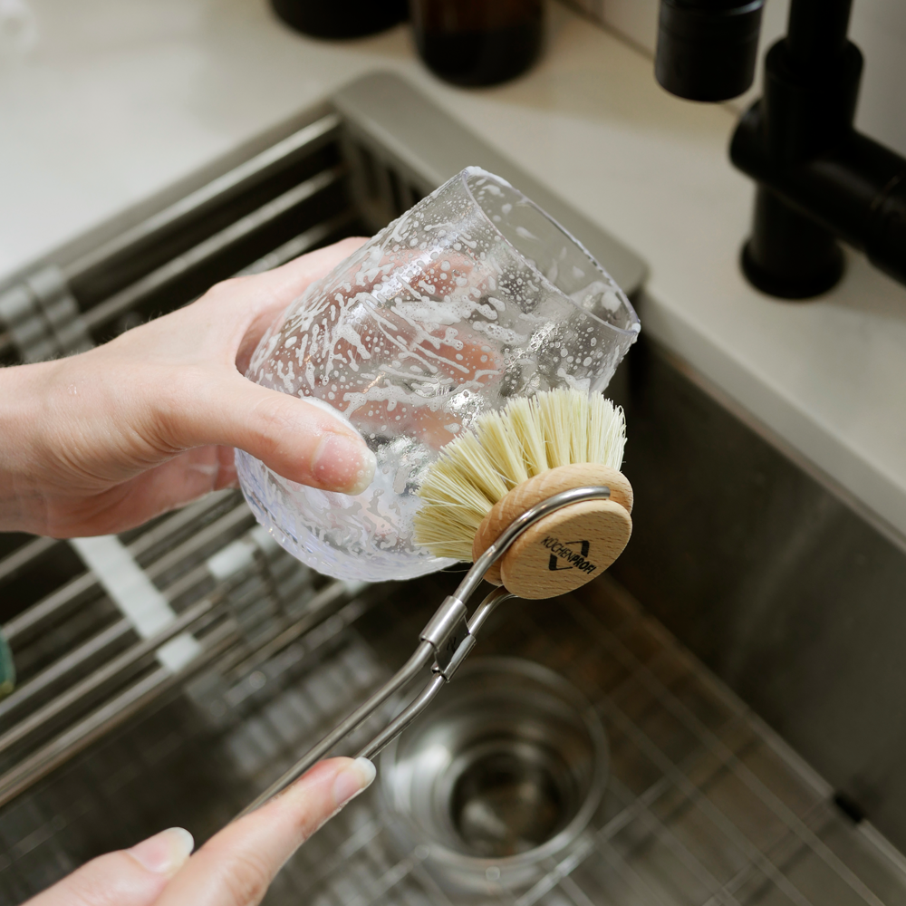 washing a glass with all natural plant based refillable dish soap