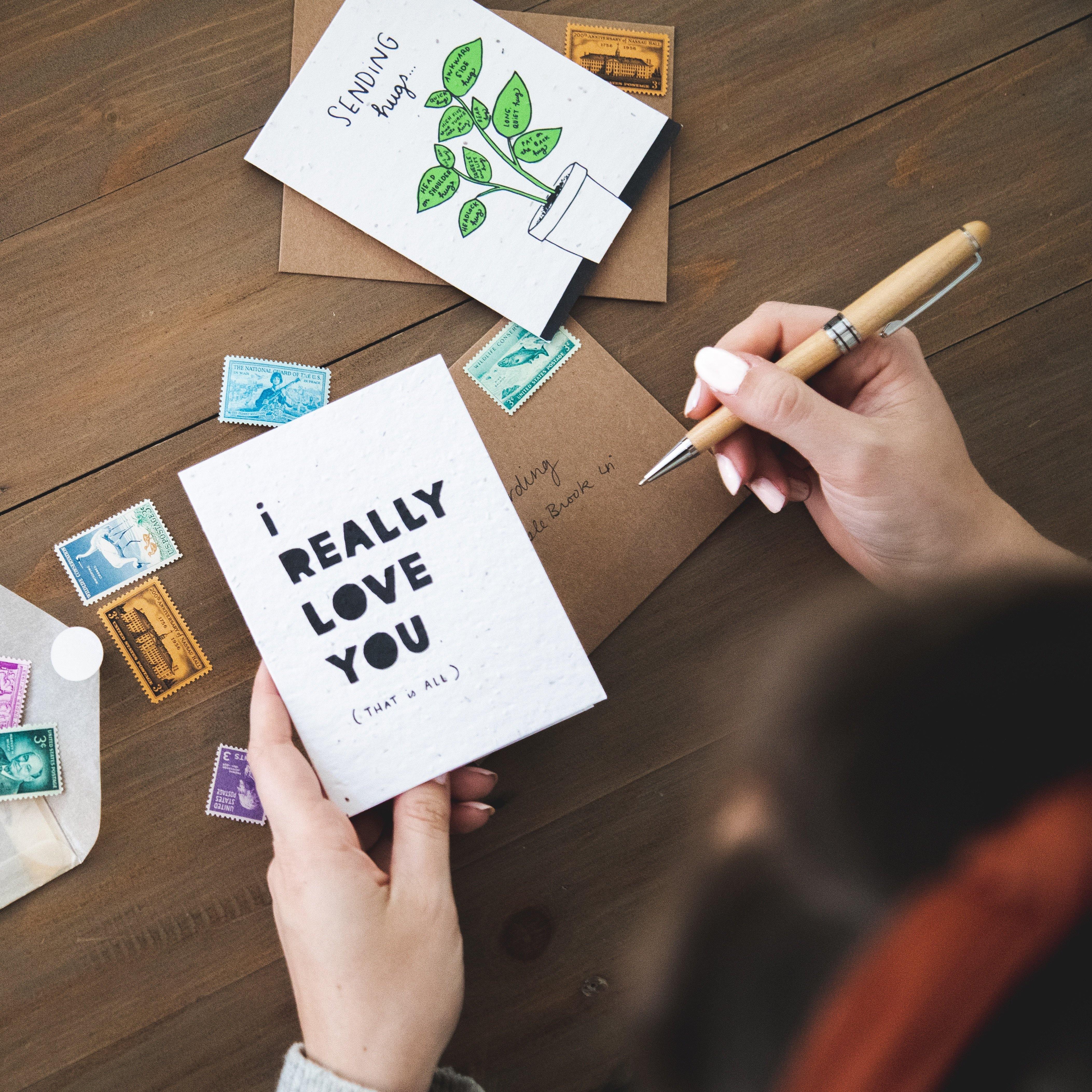 a girl sitting at a table holding a white card with black print that says "I really love you (that is all)"