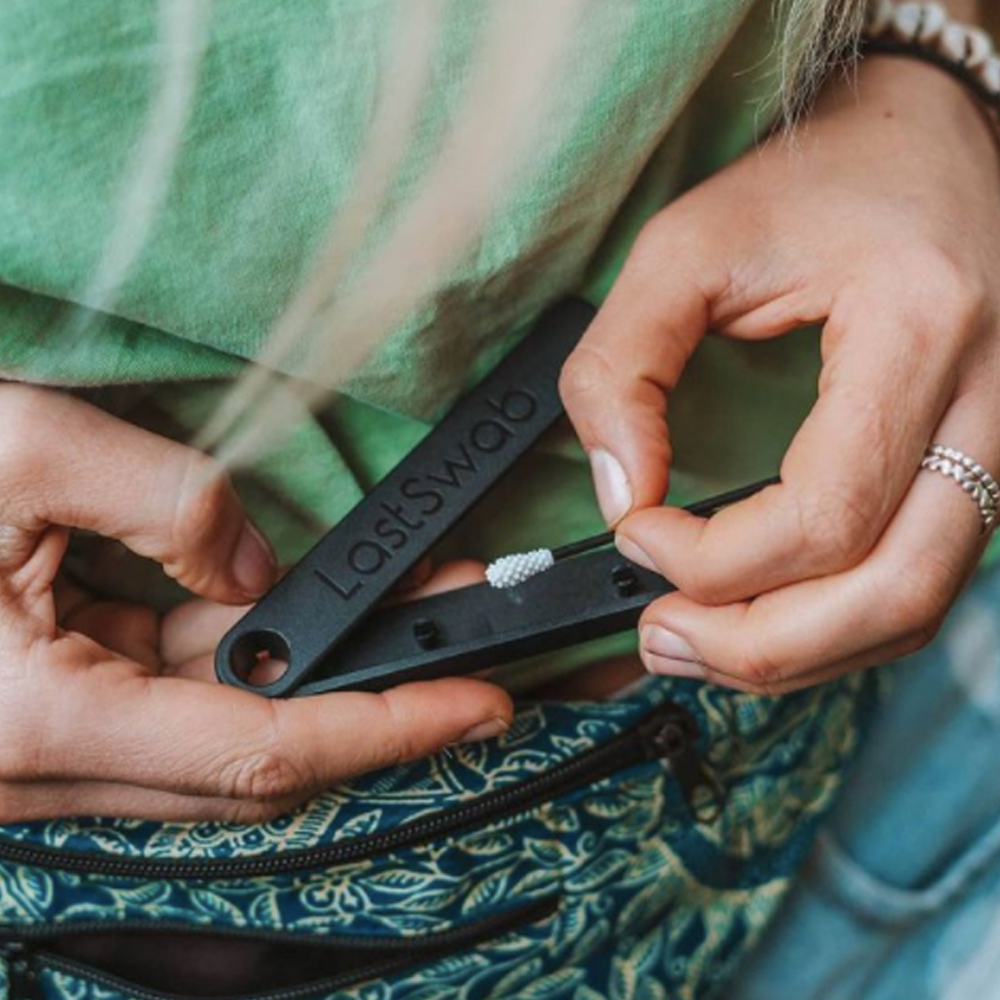 A closeup of someone taking the black reusable cotton swab from its black storage case.
