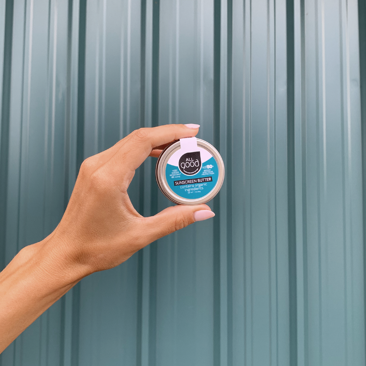 hand holding a 1oz aluminum tin of SPF 50+ mineral sunscreen butter.
