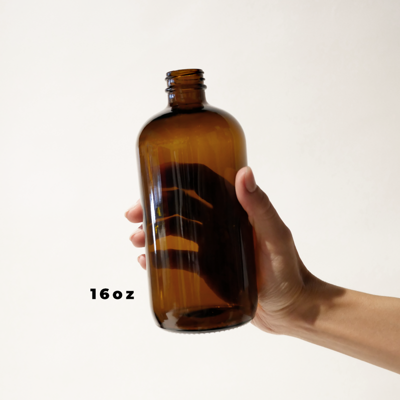 A hand holding a 16oz glass amber bottle for The Good Fill zero waste refills.