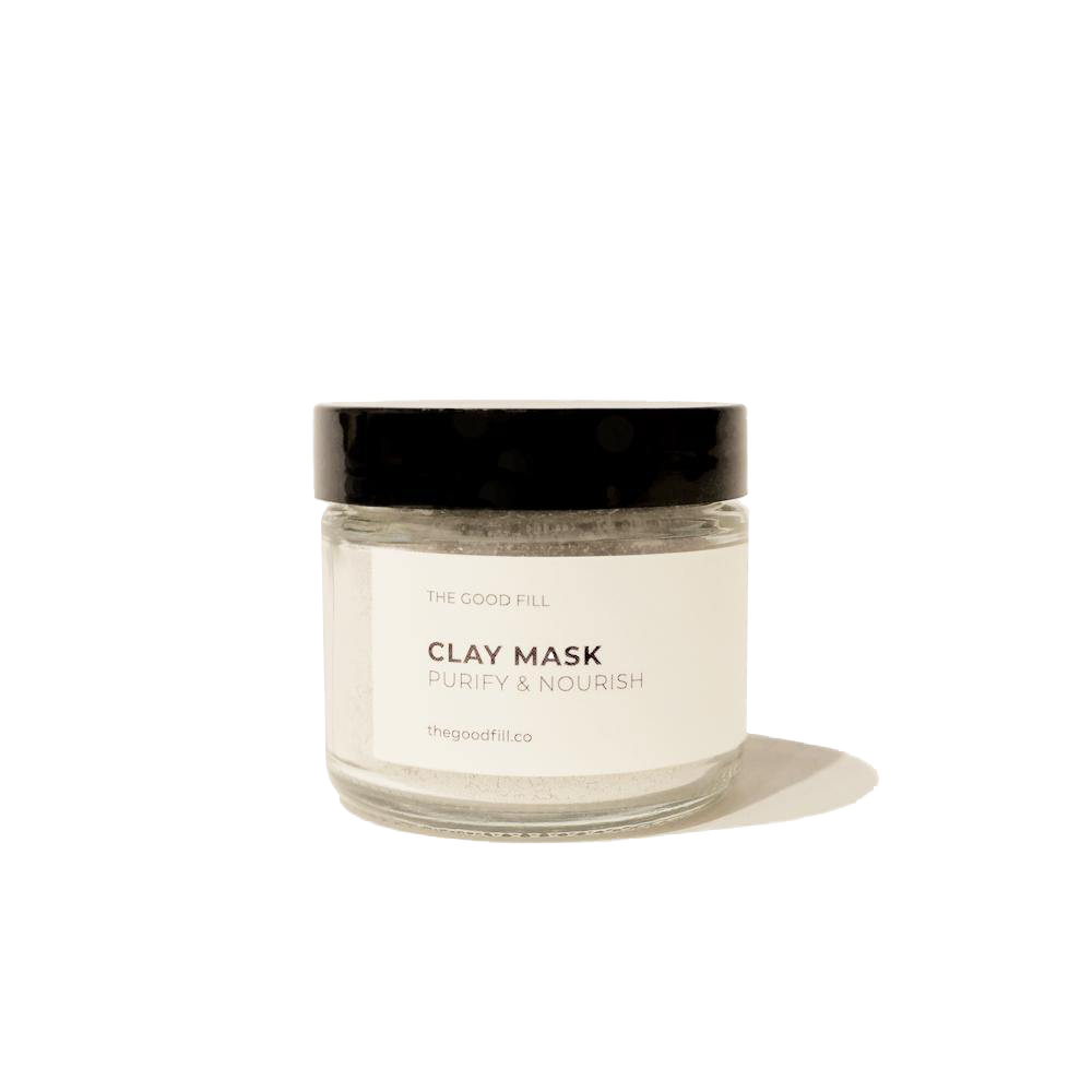 2oz. re-usable clear Good Fill glass jar filled with a light grey clay mask powder. The lid is a black twist-on lid.