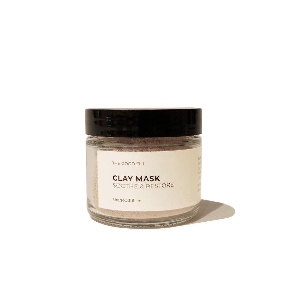 2oz. re-usable clear Good Fill glass jar filled with a light pink clay mask powder. The lid is a black twist-on lid.
