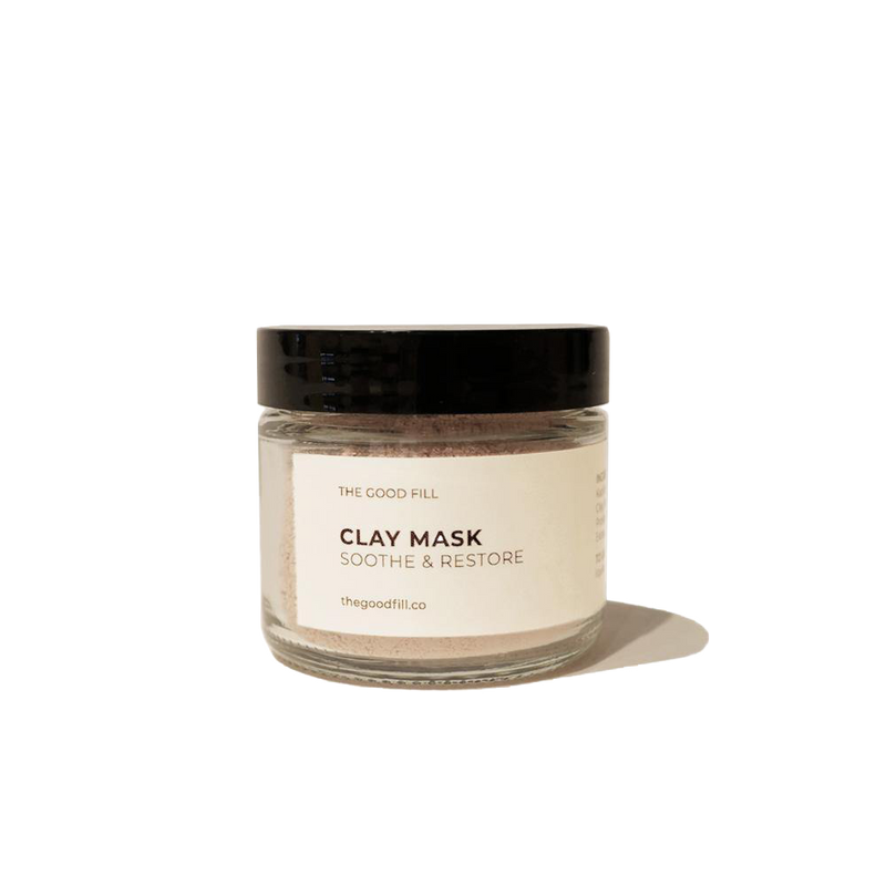 2oz. re-usable clear Good Fill glass jar filled with a light pink clay mask powder. The lid is a black twist-on lid.