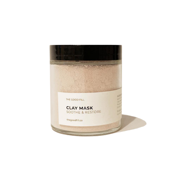 4oz. re-usable clear Good Fill glass jar filled with a light pink clay mask powder. The lid is a black twist-on lid.