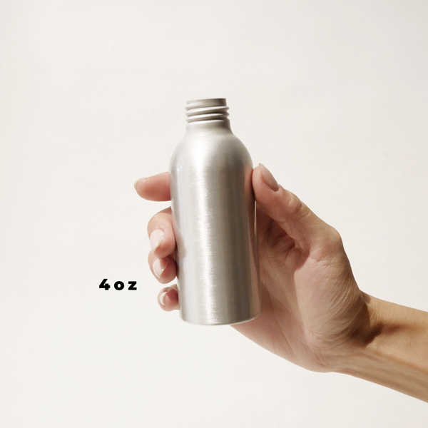A hand holding an 4oz aluminum bottle for The Good Fill zero waste refills.