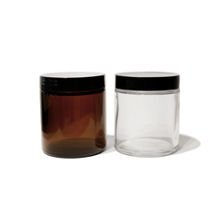 one 4oz amber glass jar with a black lid and one 4oz clear glass jar with black lid.