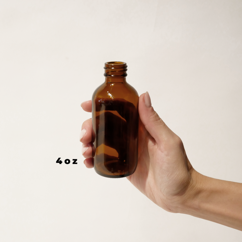 A hand holding a 4oz glass amber bottle for The Good Fill zero waste refills.