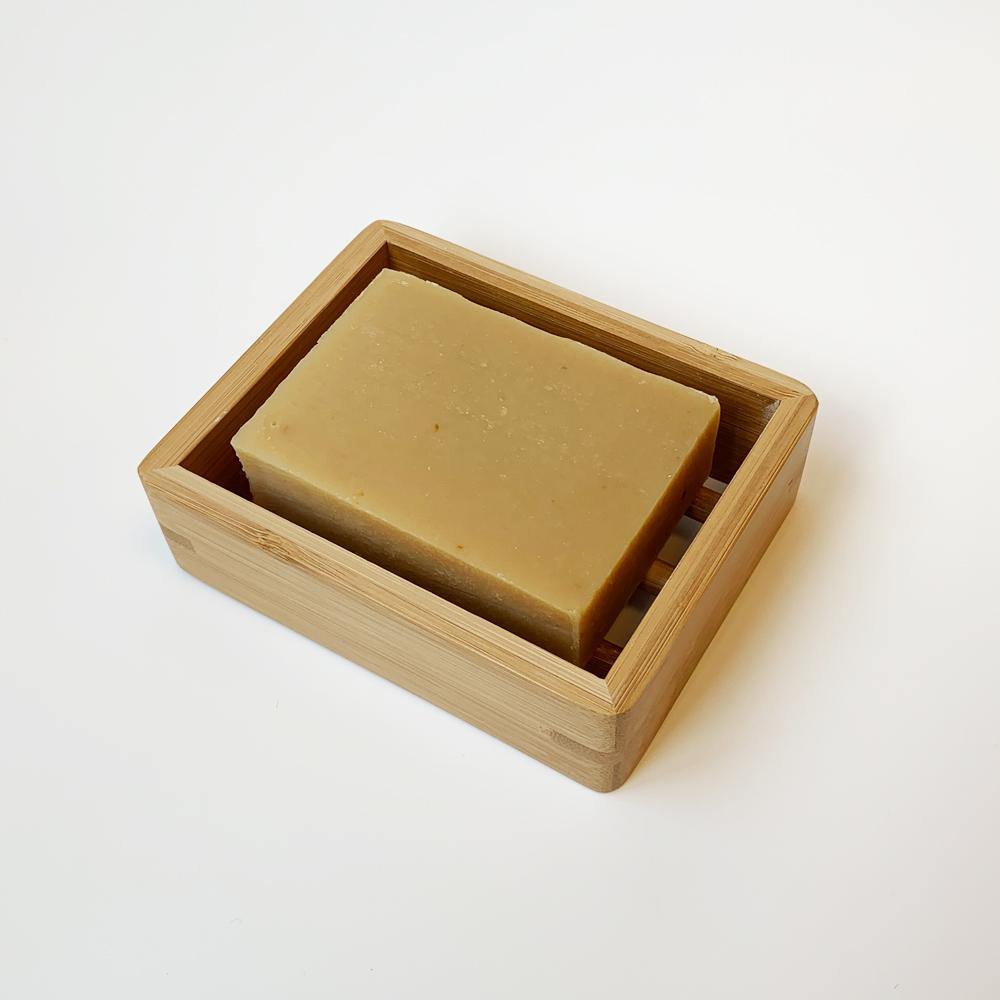product shot of brown, rectangle bamboo soap dish holding a grapefruit lemon bar of soap