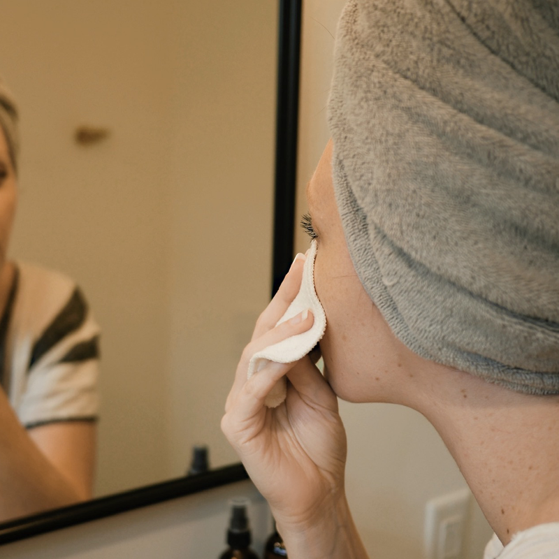 woman wiping her face with an organic cotton facial round.