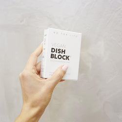 hand holding a small dish washing block that is packaged in a white paper box with bold black print.