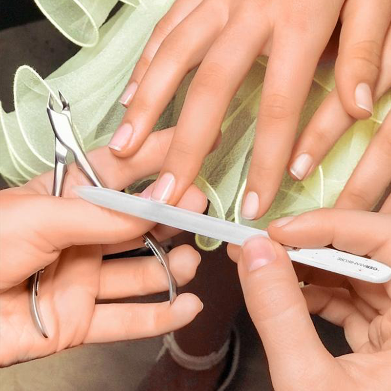 Someone using a crystal glass nail file for a manicure.