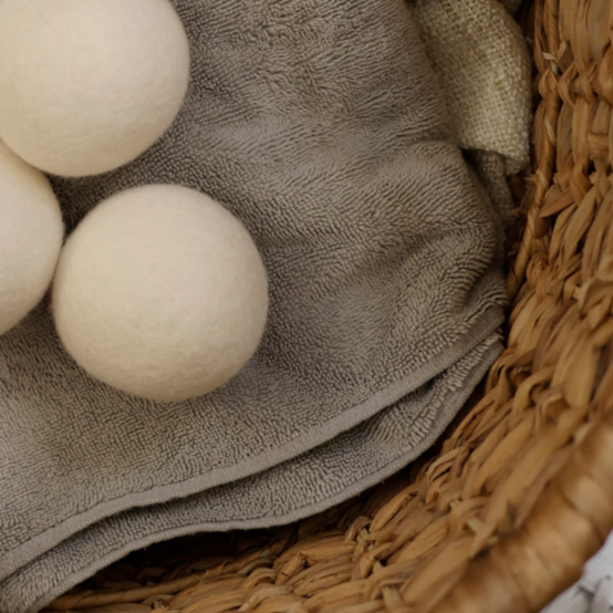 three wool dryer balls sitting on folded laundry in a basket.