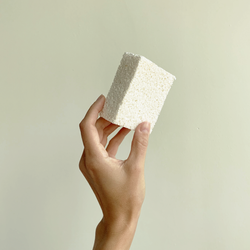 Hand holding a package free zero waste pop-up sponge.
