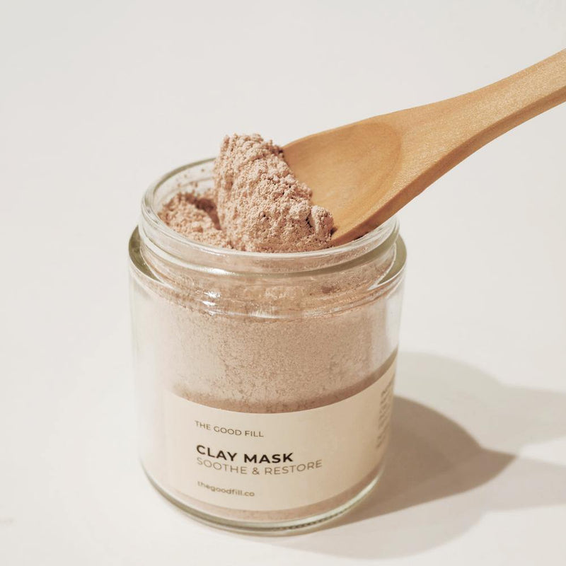 Small brown wooden spoon scooping light weight mask powder from a 4oz. reusable Good Fill glass jar.